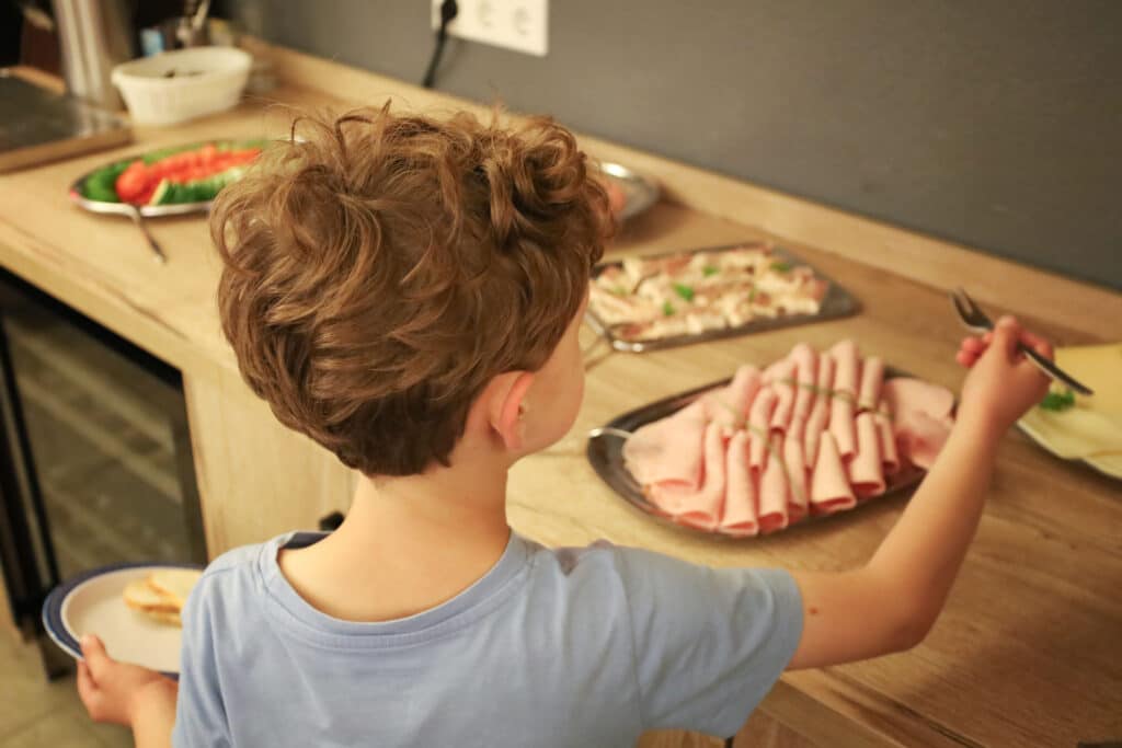 Ein Junge steht am All Inclusive Abendbuffet und sucht sich eine speise aus.